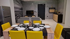 A modern dining area with a rectangular table set for four, surrounded by yellow chairs. - Red Rose.. (Iz-Zebbug)