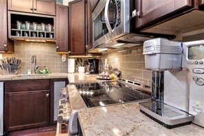 Enjoy cooking in this well-equipped kitchen with a granite countertop, stainless steel appliances, and ample storage.