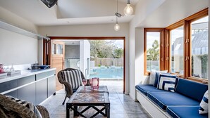 Une cuisine moderne avec un coin repas, un canapé bleu agrémenté de coussins et une vue sur une piscine.