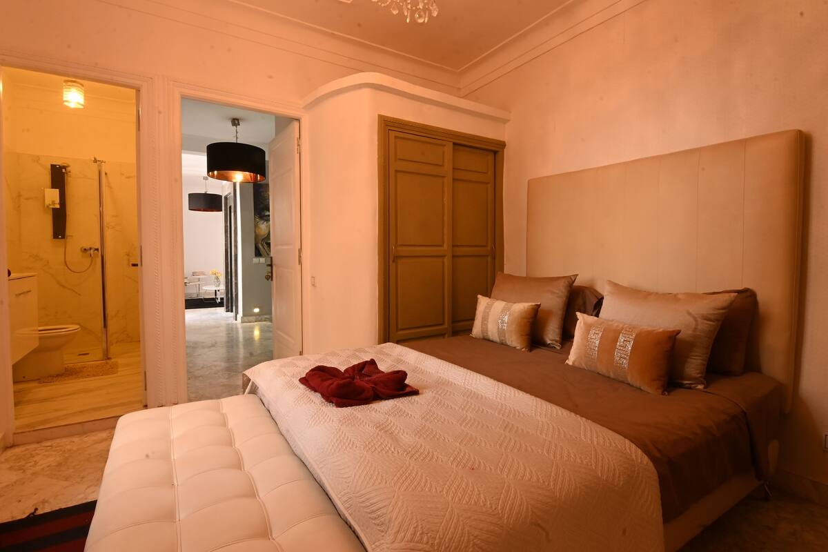 A hotel room with a large bed, a walk-in closet, and a bathroom with a shower.