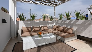 A modern outdoor seating area with a sectional sofa and a coffee table, surrounded by potted plants and a pergola. - Riad VIP (Marrakech)