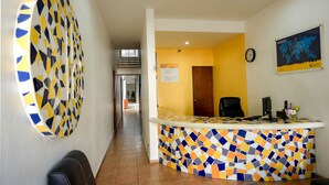 Un mostrador de recepción con un diseño de mosaico colorido, un reloj y un mapa en la pared.