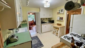 A compact kitchen with a gas stove, a sink, and a microwave. There is a dining area with a table and chairs.