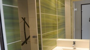 A modern bathroom with a glass shower enclosure, a wooden vanity with a sink, and a mirror above the vanity.