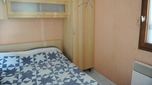 A bedroom with a bed, a wooden wardrobe, and a radiator.