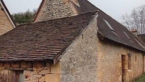 Un edifici de pedra amb teulada inclinada i xemeneu.