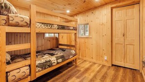Une chambre avec un lit superposé, des murs en bois et une fenêtre.
