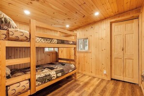 Een slaapkamer met stapelbedden, houten wanden en een raam.