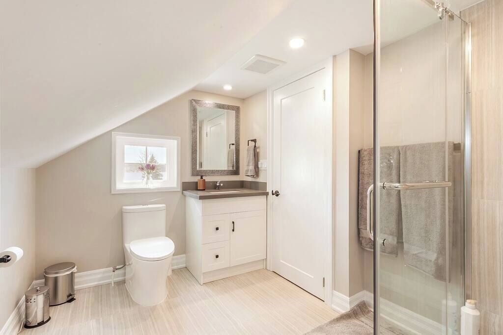 A modern bathroom with a toilet, vanity, and shower.