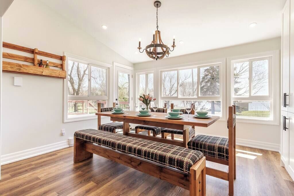 A spacious kitchen with a wooden bench, large windows, and a chandelier.