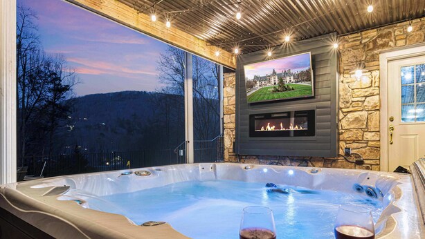 A hot tub with two glasses of red wine, a stone fireplace, and a TV on the wall. - 7k SqFt Estate - Epic Amenities & Fun - Sleeps 20 (Biltmore Forest)