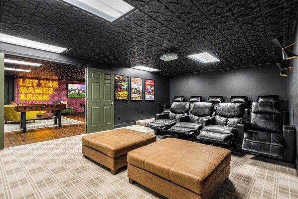 A home theater with a projector screen, reclining chairs, and a small table with a bench.