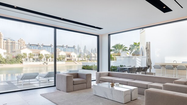 Amplia sala de estar con ventanas grandes que ofrecen vista a una playa y al horizonte de la ciudad.