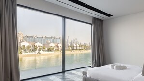 Habitación de hotel con un ventanal que ofrece vistas a la playa y al paisaje urbano.