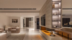 Una sala moderna con un televisor grande, una estantería empotrada y un área de descanso.
