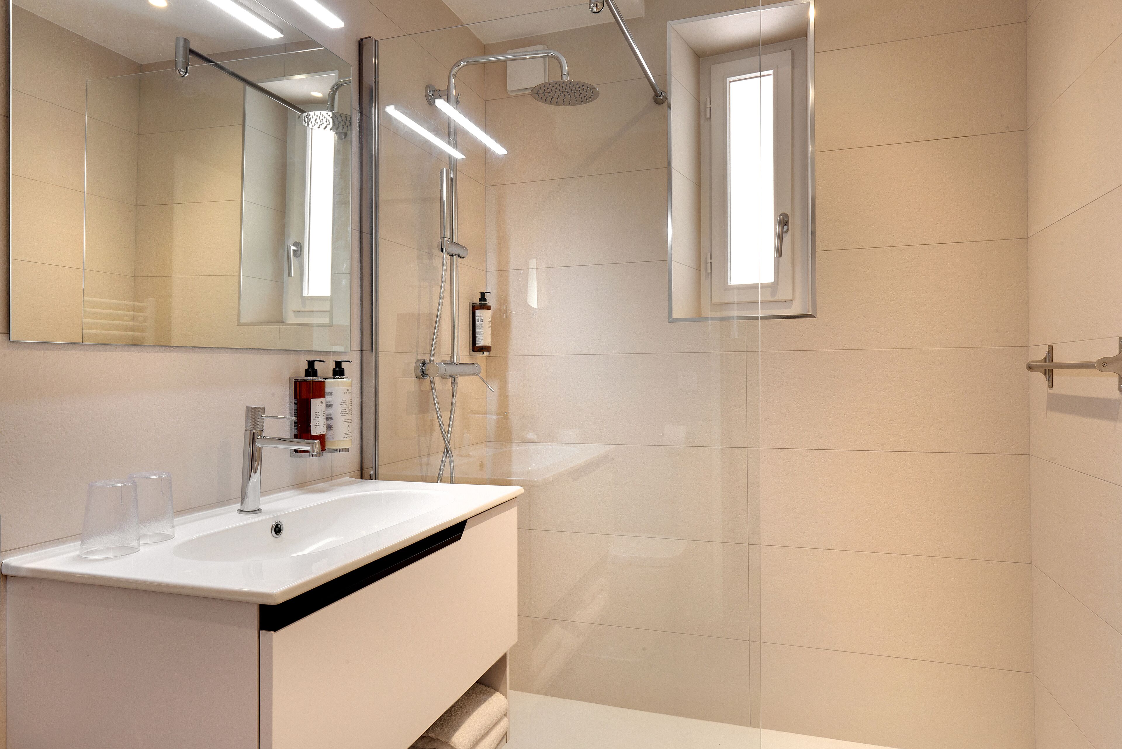A modern bathroom with a large mirror, a sink, and a shower.