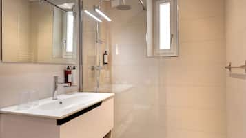 Un baño moderno con un espejo grande, un lavamanos y una ducha.