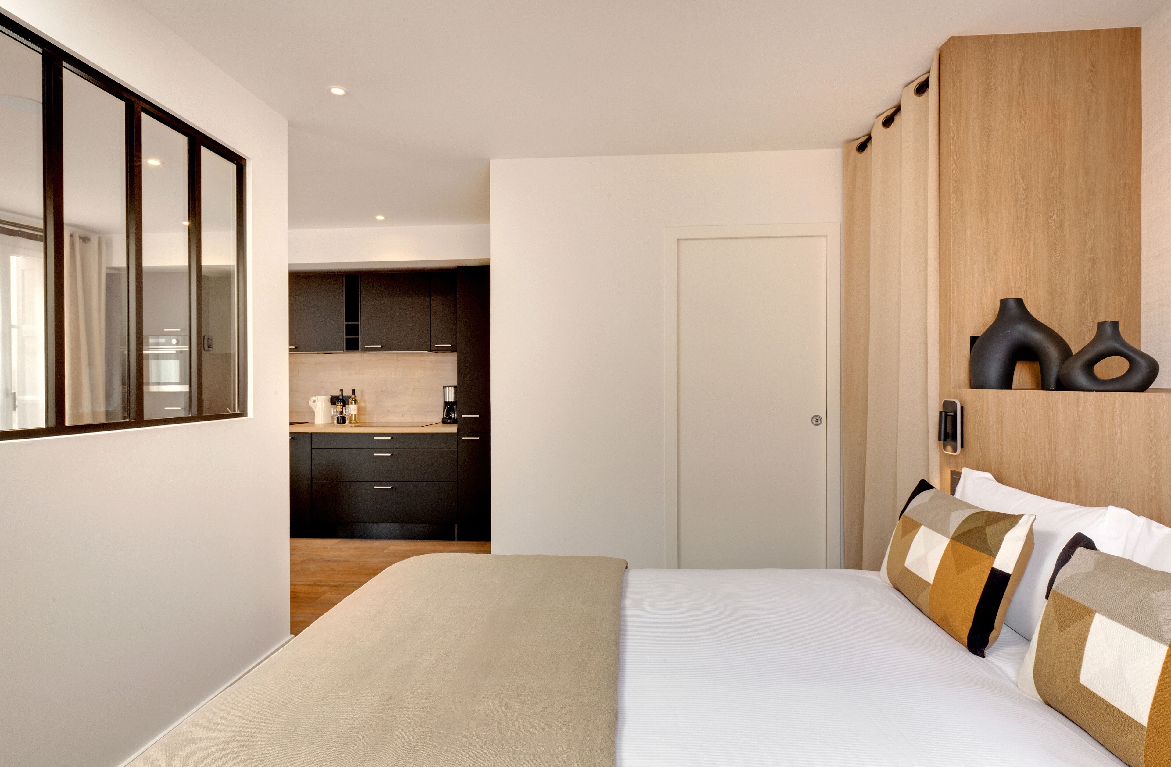Et moderne hotelværelse med en stor seng, et træskab, et tekøkken og et badeværelse.