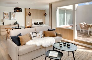 A modern hotel room with a sofa, a dining table, a bed, and a balcony with outdoor seating. - Les Appartements de Collioure (Collioure)