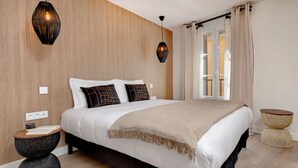 Un dormitorio moderno con una cama grande, dos mesitas de noche y un ventanal con cortinas.