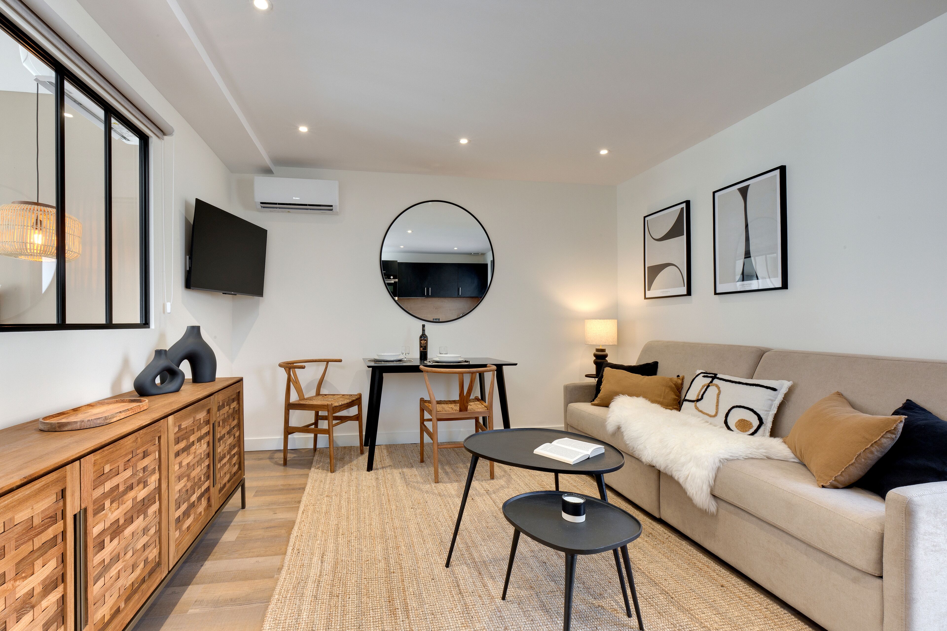 Uma sala de estar moderna com sofá, mesa de centro, mesa de jantar, cadeiras e uma TV fixada na parede.