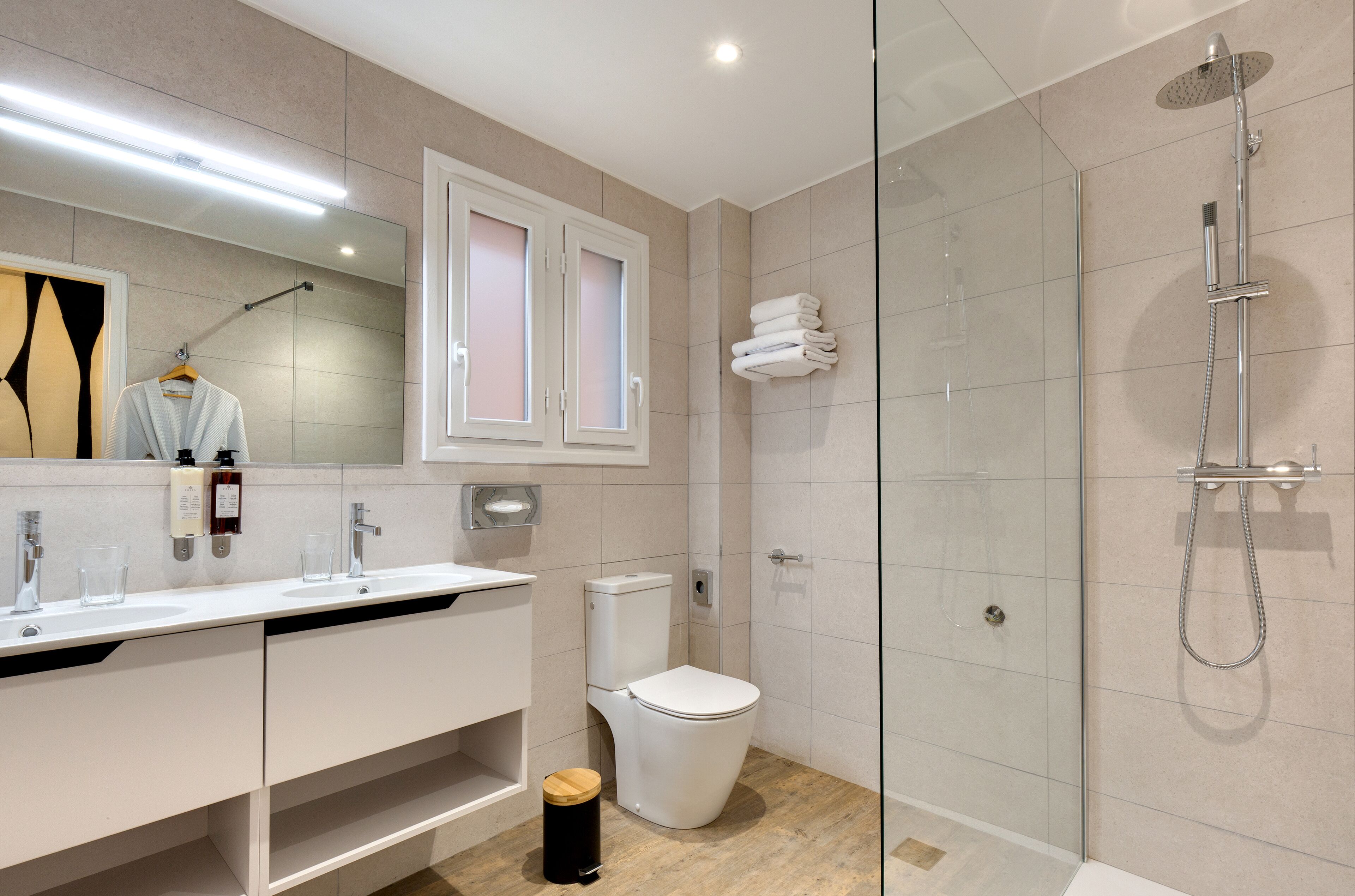 Un baño moderno con ducha envuelta en vidrio, inodoro blanco y tocador con espejo.