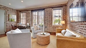Ein Wohnzimmer mit Backsteinwand, einem runden gewebten Couchtisch und zwei Sofas.