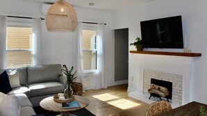 Een woonkamer met een bank, een salontafel, een open haard en een televisie erboven.