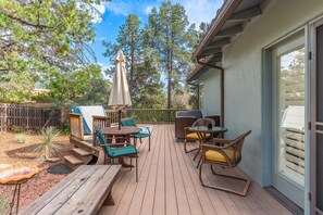 A wooden deck with outdoor furniture, including a table and chairs, and a covered area with an umbrella. - Walk to Trails, Private Hot Tub, Red Rock Views, 3BR with 2 Kings, Sunset Deck (Sedona)