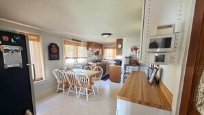 A compact kitchen with a dining area, a refrigerator, and a microwave. - Charming Cottage - Northeast River / Chesapeake Bay (Perryville)