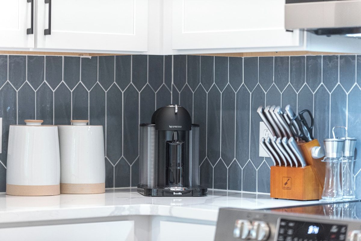 A kitchen with a coffee machine, two white containers, and a knife block.