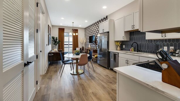 A modern kitchen with a central island, built-in appliances, and a dining area with a round table and chairs.