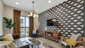 A modern living room with a patterned wall, a television, and comfortable seating.