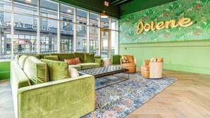 A green-themed lounge area with a large window, a patterned rug, and a wall with the word 'Dolene' illuminated.