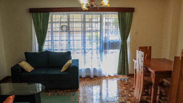 A living room with a sofa, a glass coffee table, a dining table with chairs, and a patterned floor. - HAZINA ESTATE SOUTH B (Nairobi)