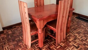 A wooden dining table with four chairs, set on a patterned wooden floor. - HAZINA ESTATE SOUTH B (Nairobi)