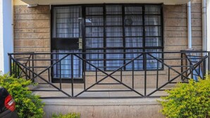 A building entrance with a metal gate, a window with a black frame, and a door. - HAZINA ESTATE SOUTH B (Nairobi)