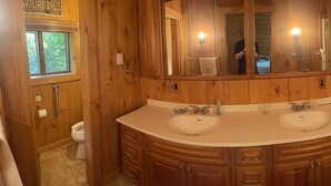 Une salle de bain en bois avec deux lavabos, un grand miroir et une douche.