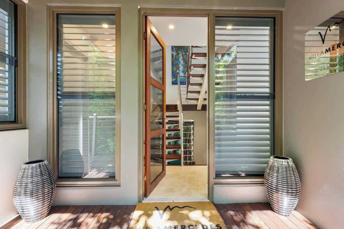 A modern interior with a wooden staircase, a door leading to a room, and two decorative vases.