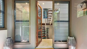 A modern interior with a wooden staircase, a door leading to a room, and two decorative vases.