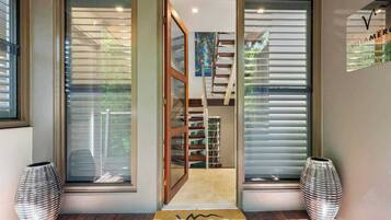 A modern interior with a wooden staircase, a door leading to a room, and two decorative vases.