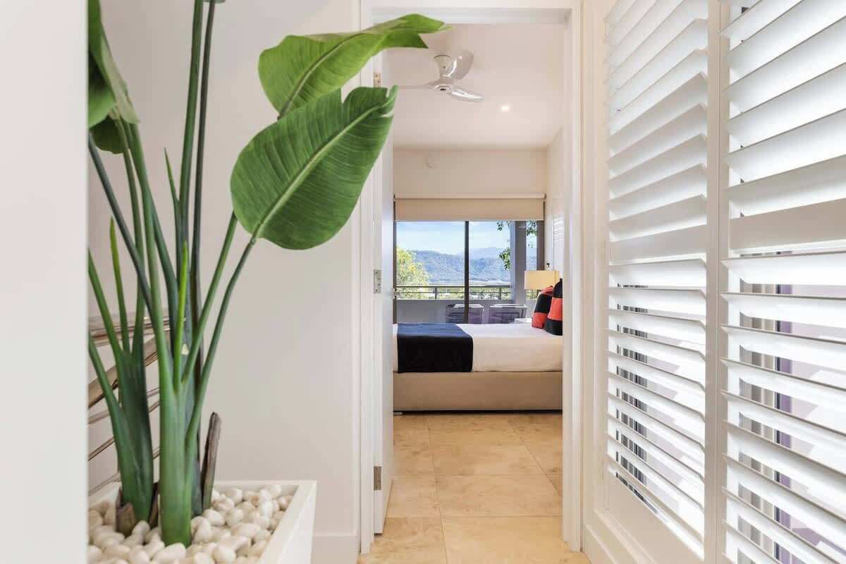 A hotel room with a bed, a view of the outdoors, a ceiling fan, and a plant.