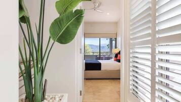 A hotel room with a bed, a view of the outdoors, a ceiling fan, and a plant.