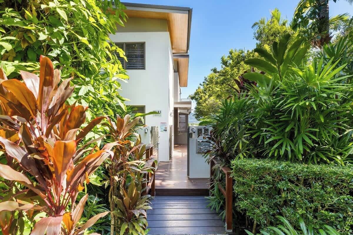 A pathway leading to a building with a white exterior and a wooden deck.