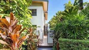 A pathway leading to a building with a white exterior and a wooden deck.