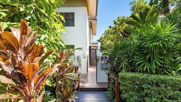 A pathway leading to a building with a white exterior and a wooden deck.