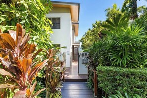 A pathway leading to a building with a white exterior and a wooden deck.