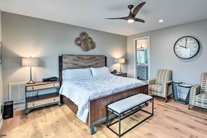 A bedroom with a bed, bedside tables, a bench, a ceiling fan, a clock, and patterned chairs. - Beautiful Nashville Home Near Downtown w/ Hot Tub! (Nashville)