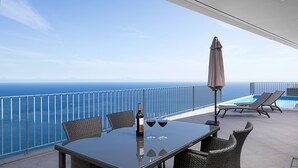 Un balcon avec une table, des chaises et une bouteille de vin.