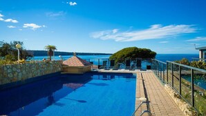 Ein Pool mit Steinmauer und Meerblick.